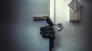 Home being broken into by a burglary attempt. Door opened slightly with gloved hand reaching in.